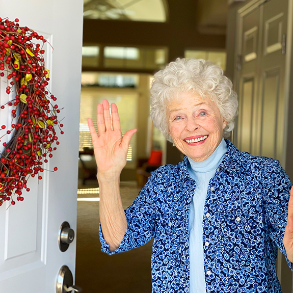 woman waving and standing in a doorway